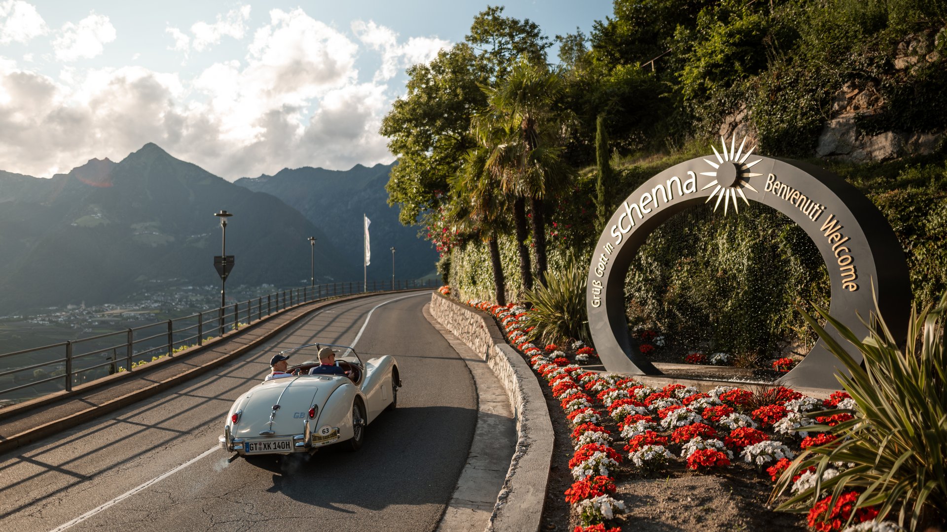 Oldtimer auf Bergstraße bei Scheffau mit Blumen und Willkommensschild
