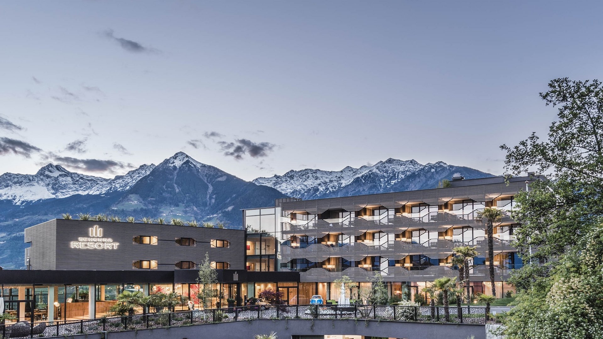 Modern resort with snowy mountains in the background at dusk