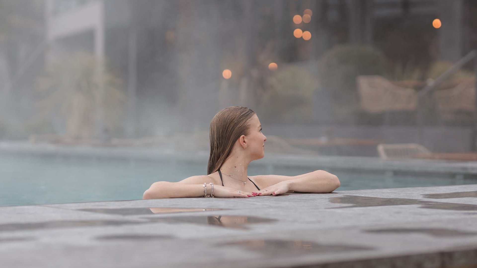 Frau entspannt im Außenpool mit Dampf im Hintergrund
