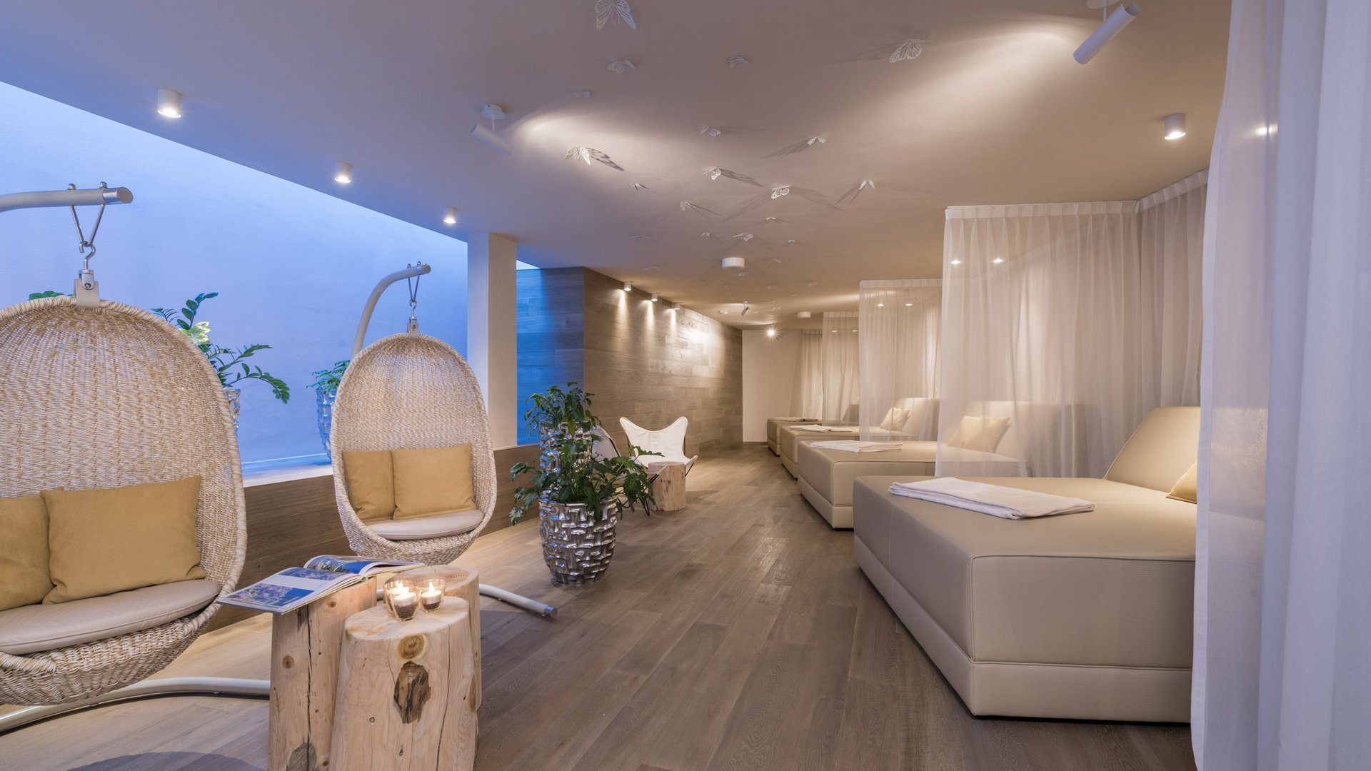 Modern spa area with hanging chairs and lounge beds with curtains