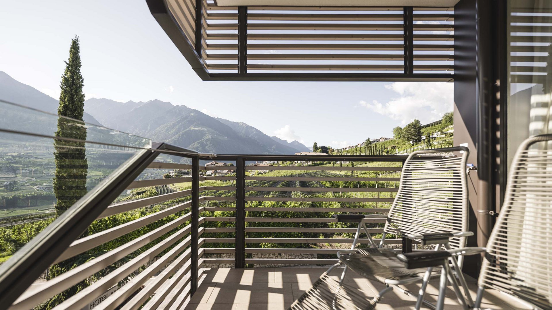 Balcone con sedie e vista su vigneti verdi e montagne sotto un cielo limpido