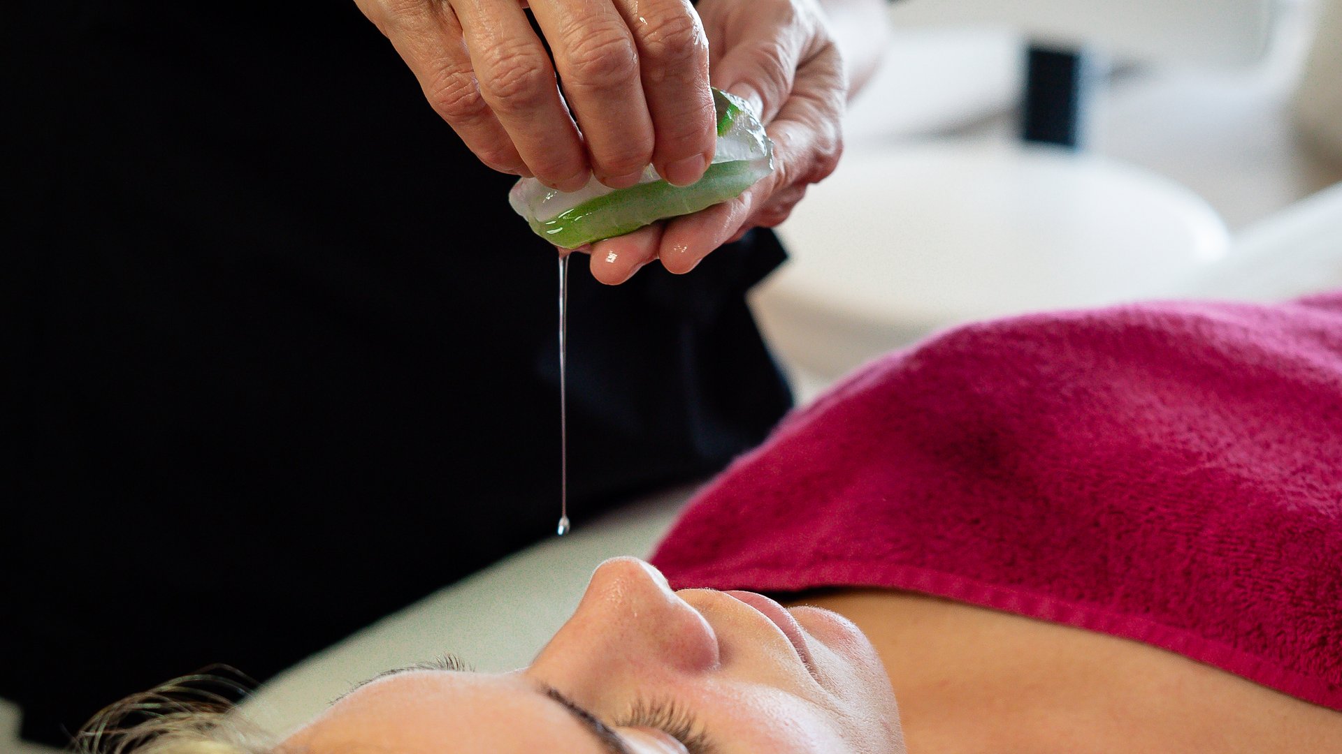Kosmetikerin presst Aloe-Vera-Gel über Frau im Spa