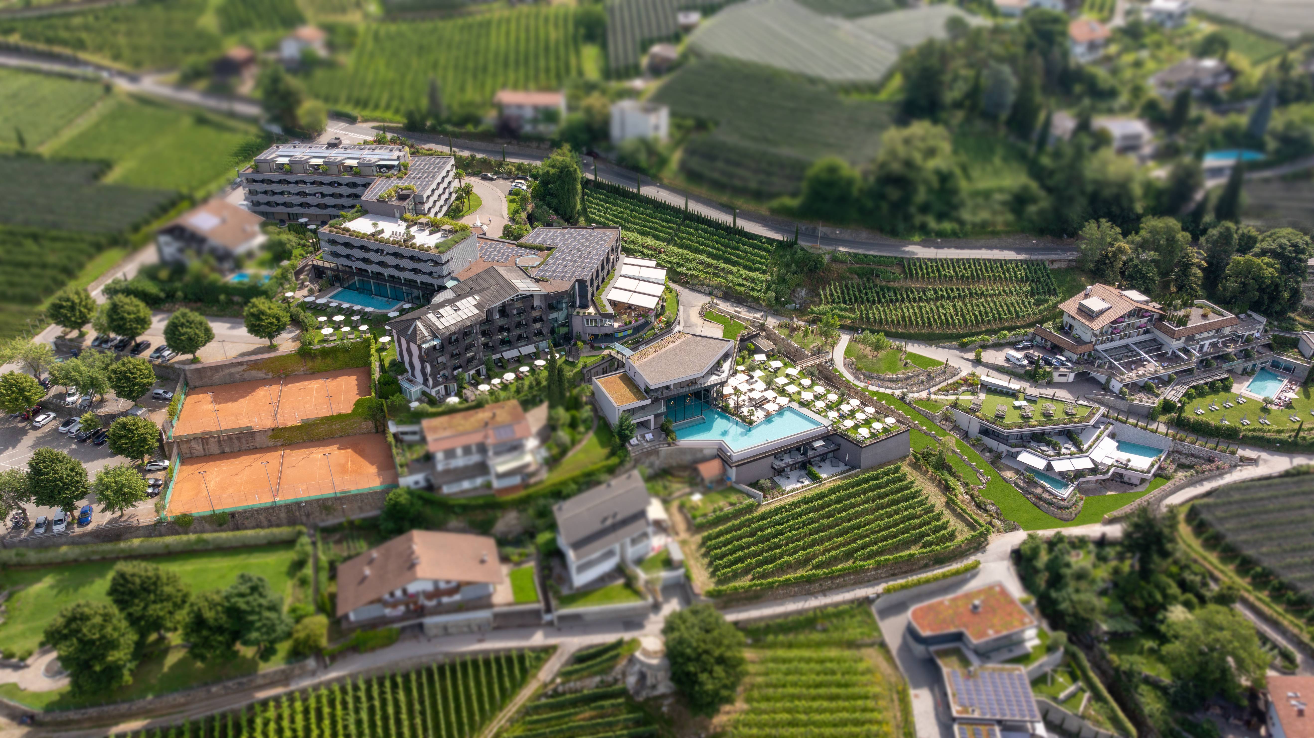 Luftaufnahme eines Resorts mit Tennisplätzen und Pools umgeben von Weinbergen
